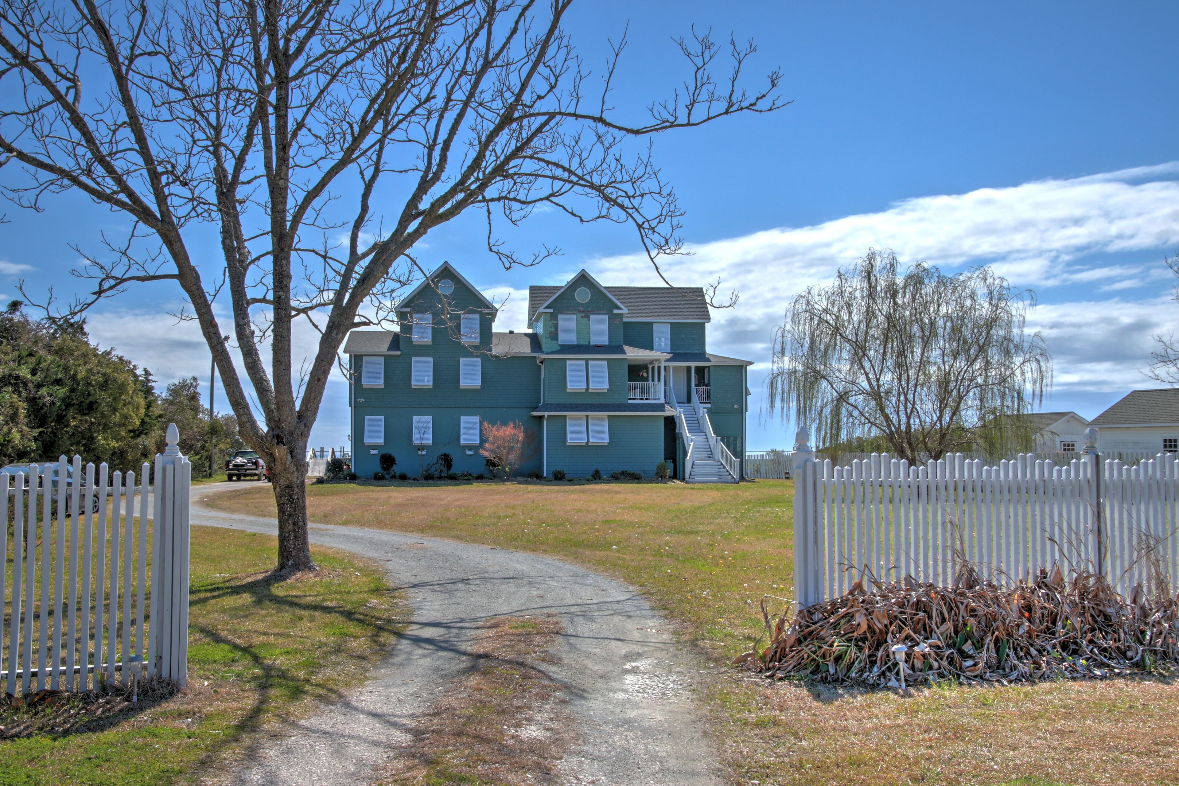 The white picket fence and beautiful trees lead the way to this seaside oasis.