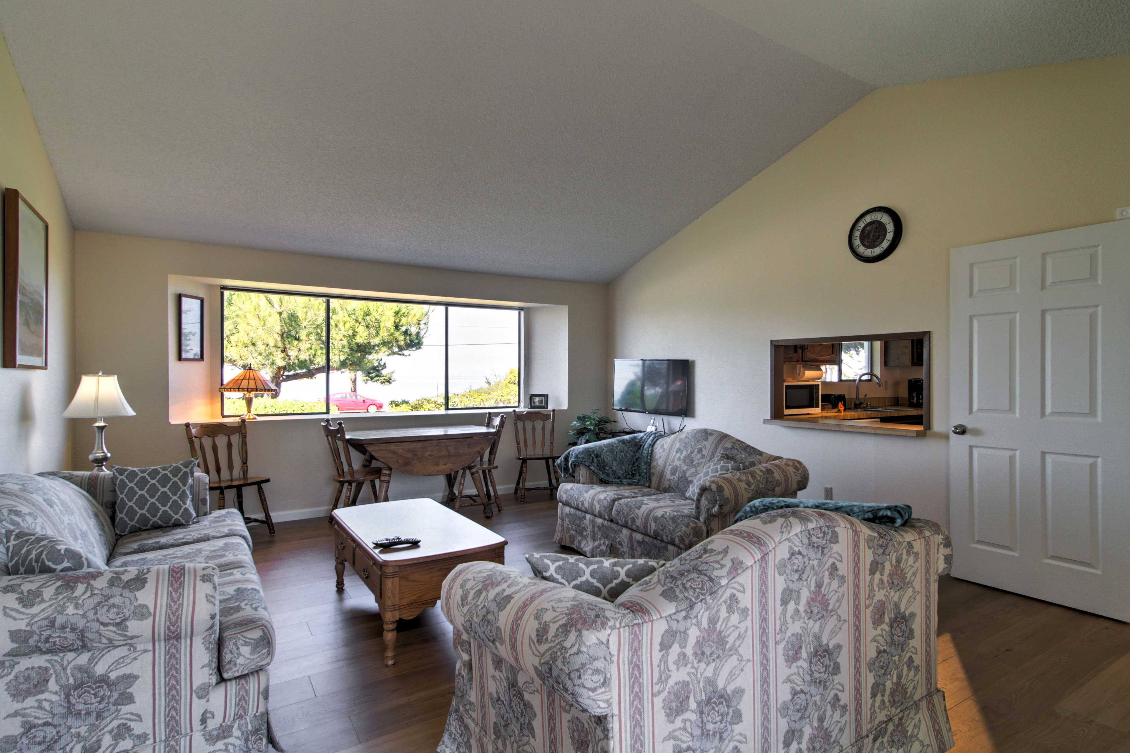 This living room has comfy furniture with a pass-through kitchen window.