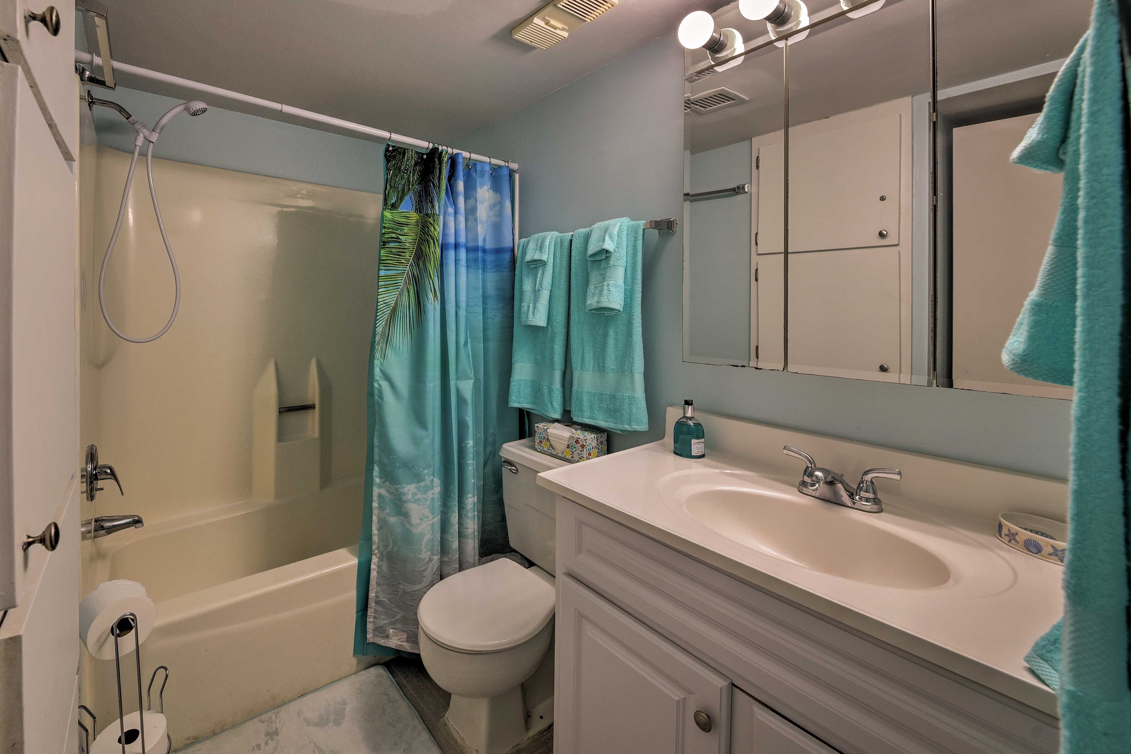 The bathroom houses a mirrored vanity and tub/shower combo.