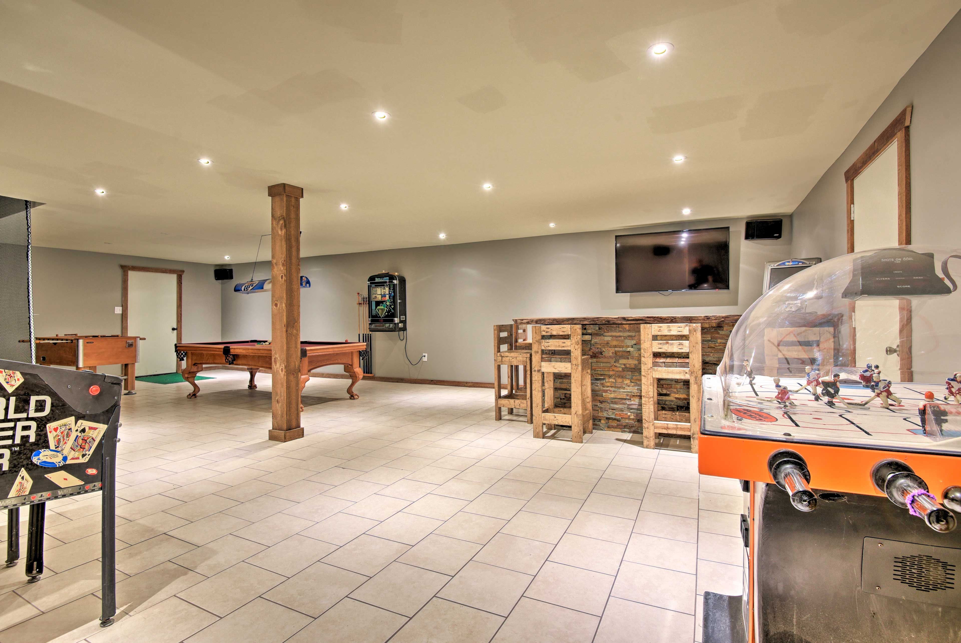 The game room has a hockey foosball table, large bar, and flat-screen TV.