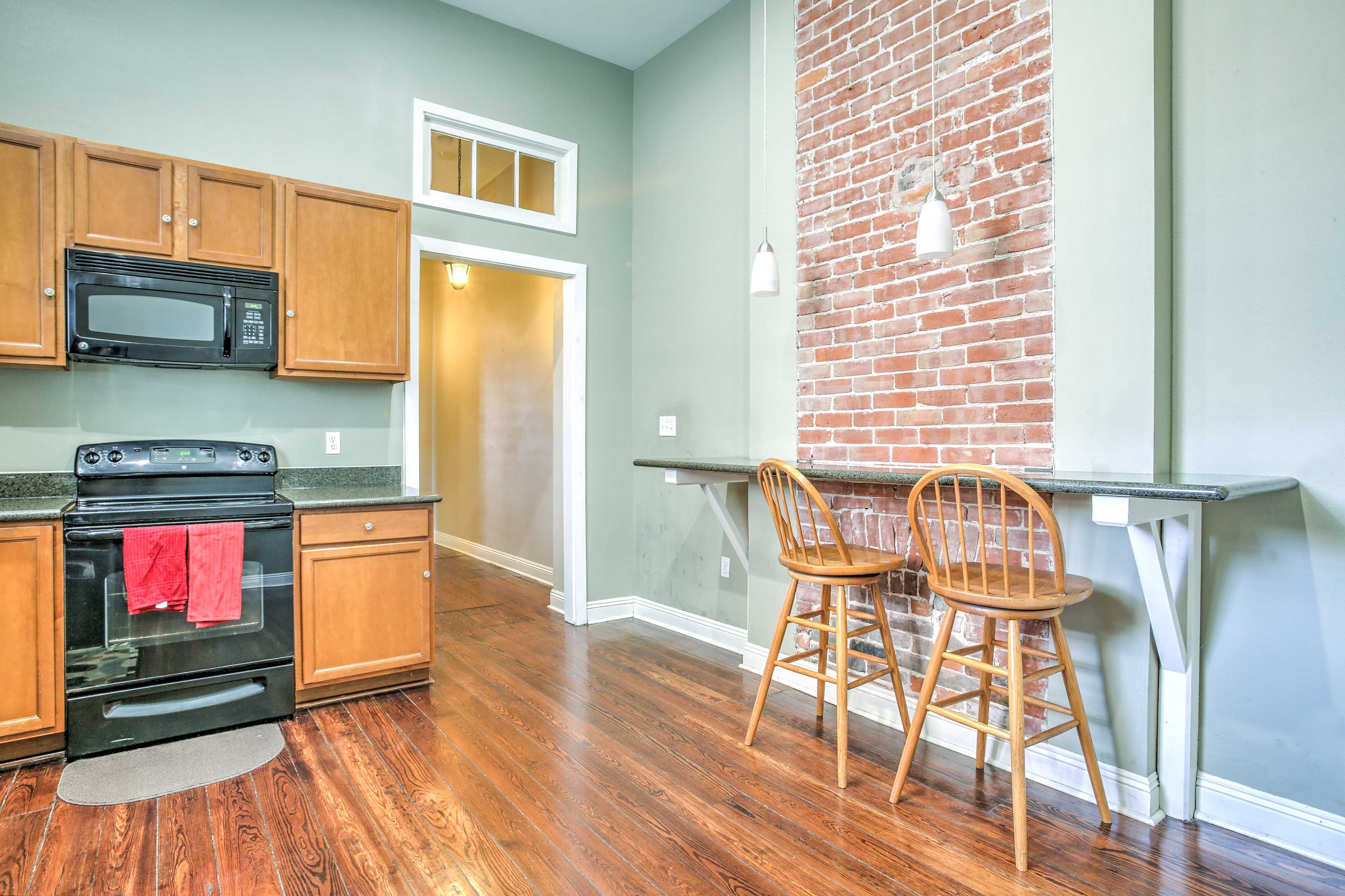 A built-in counter and exposed brick wall detail the fully equipped kitchen.