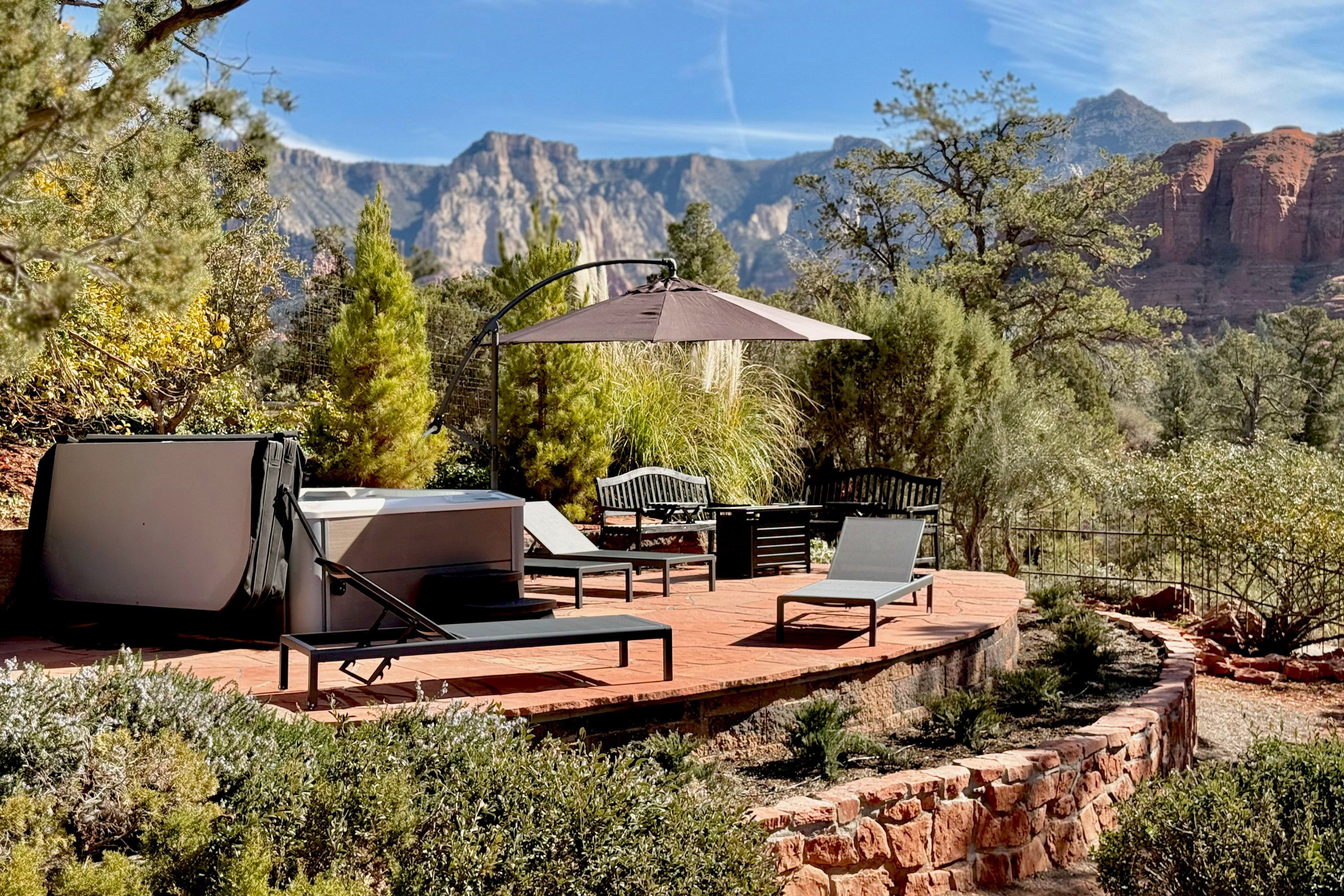 Stone terrace with hot tub, loungers, and 270-degree red rock canyon panorama