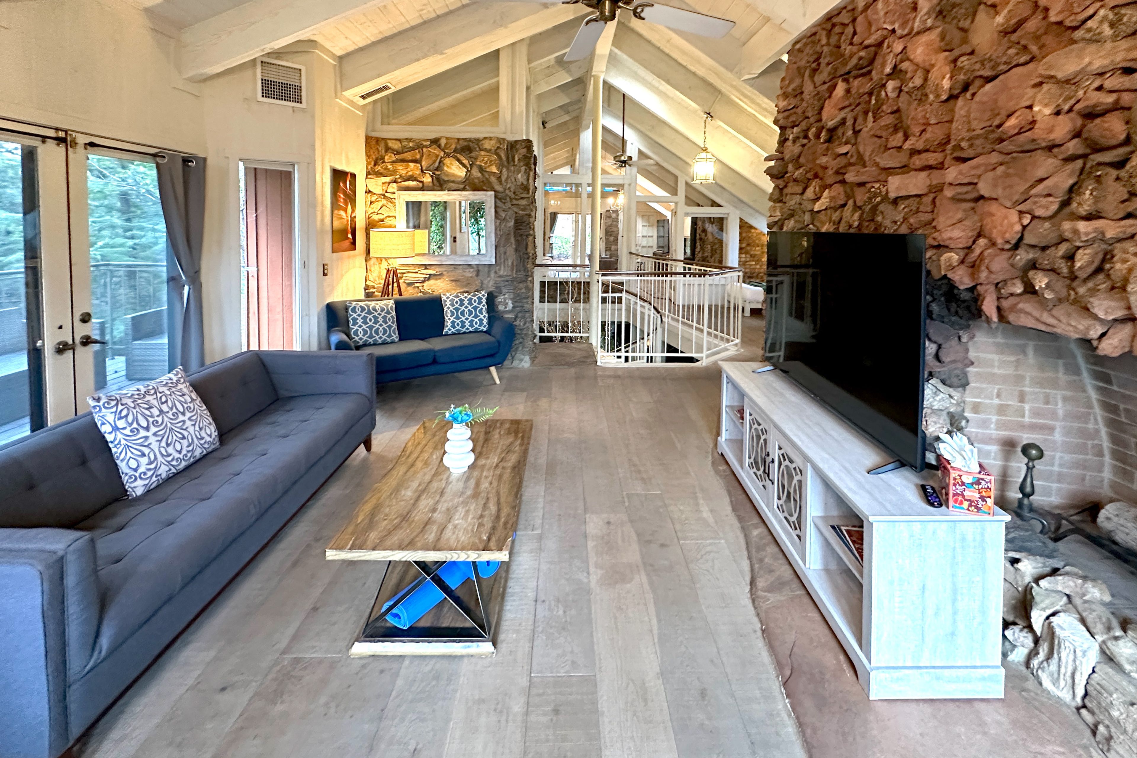 Living room w/ high ceilings, spiral staircase, stone walls, natural light