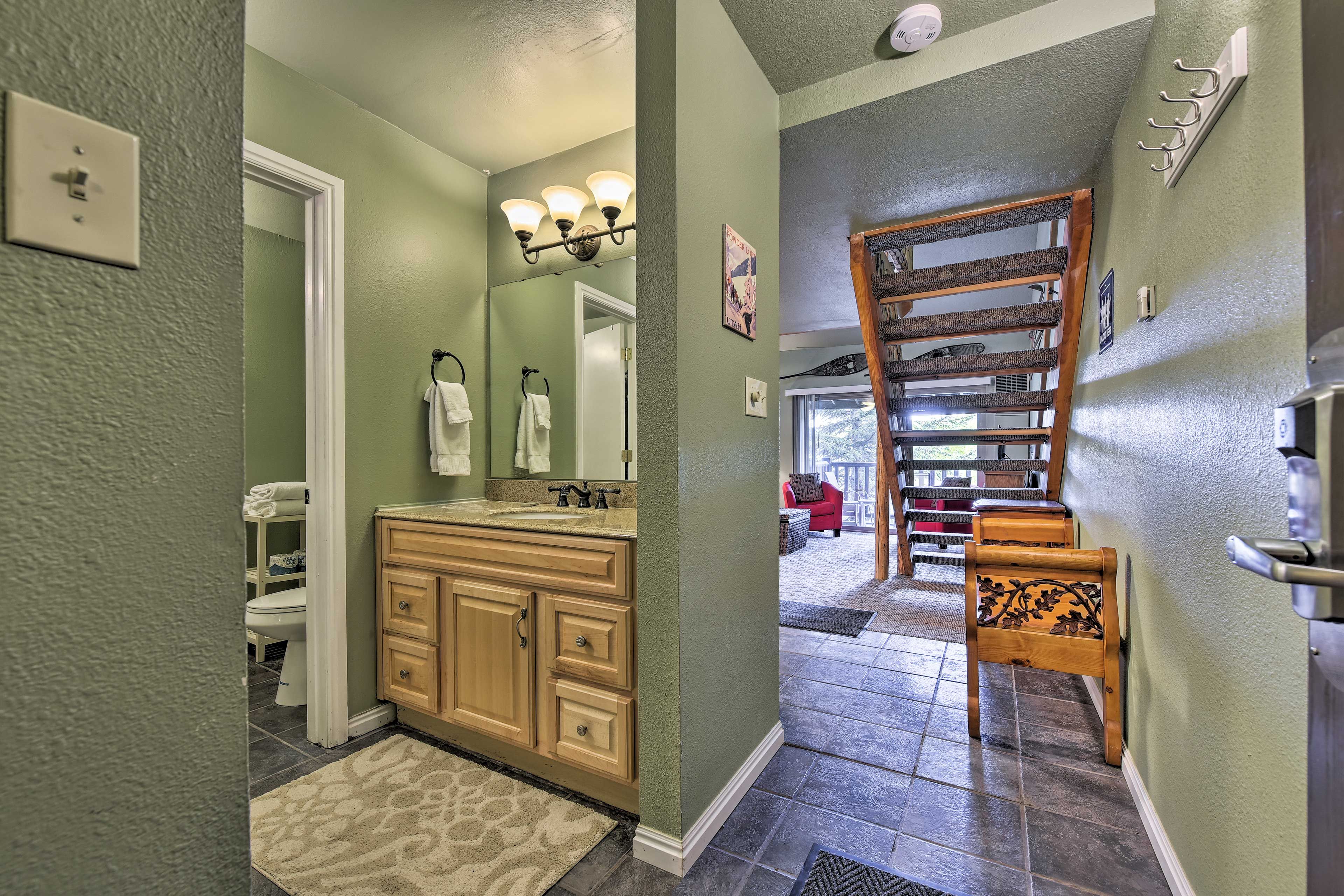 The bathroom also contains a mirrored vanity and tub/shower combo.