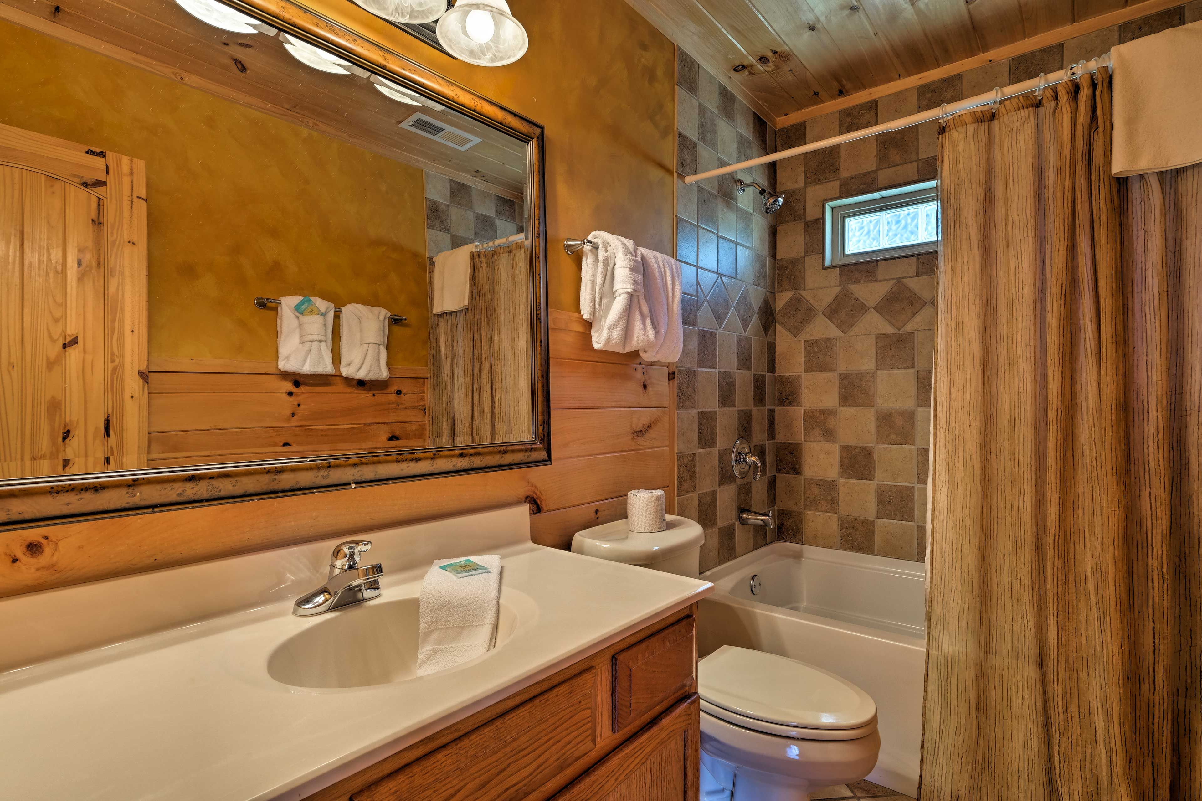 This full bathroom boasts a shower/tub combo paired with rustic accents.