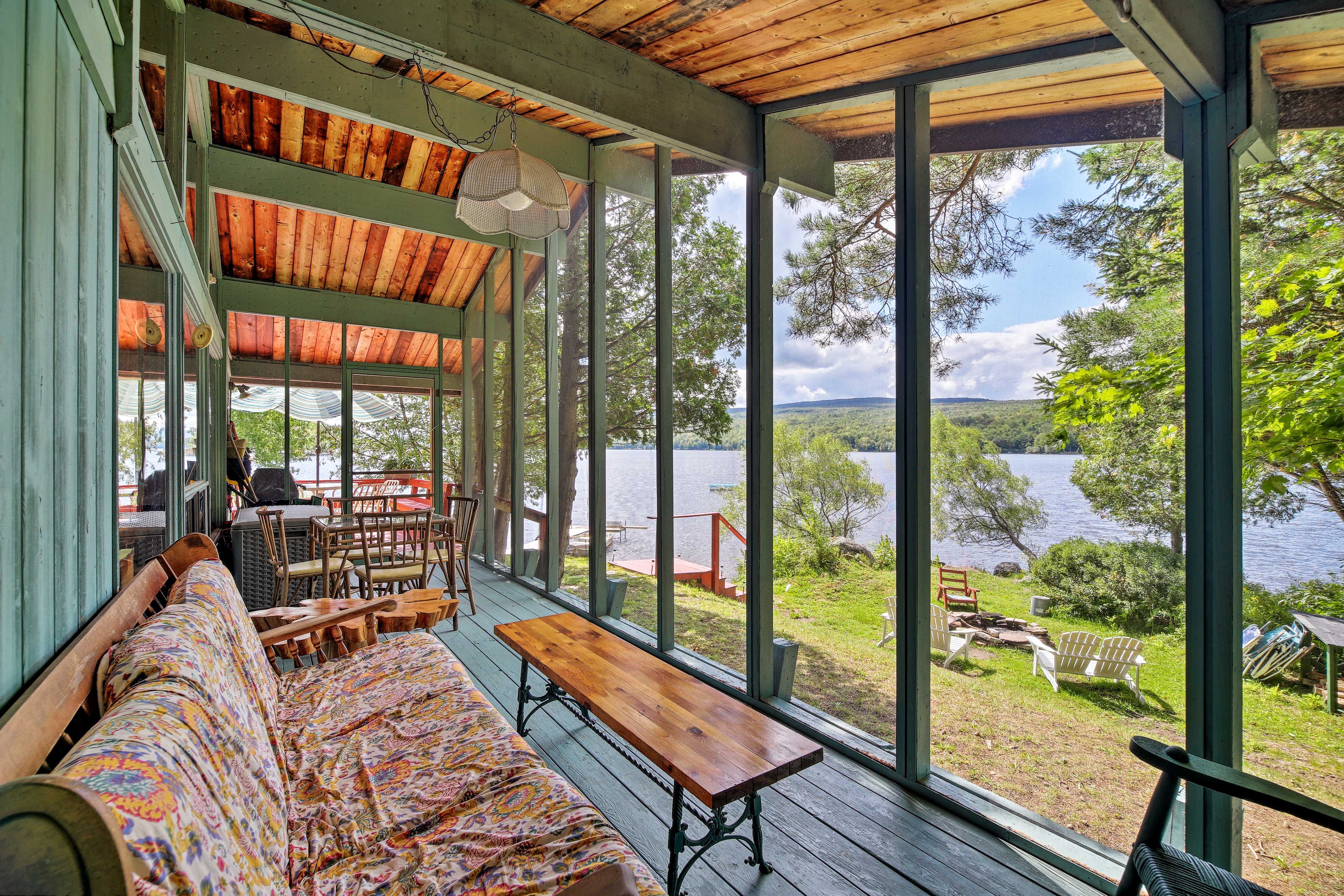 The screened-in porch offers an outdoor dining table and comfortable seating.