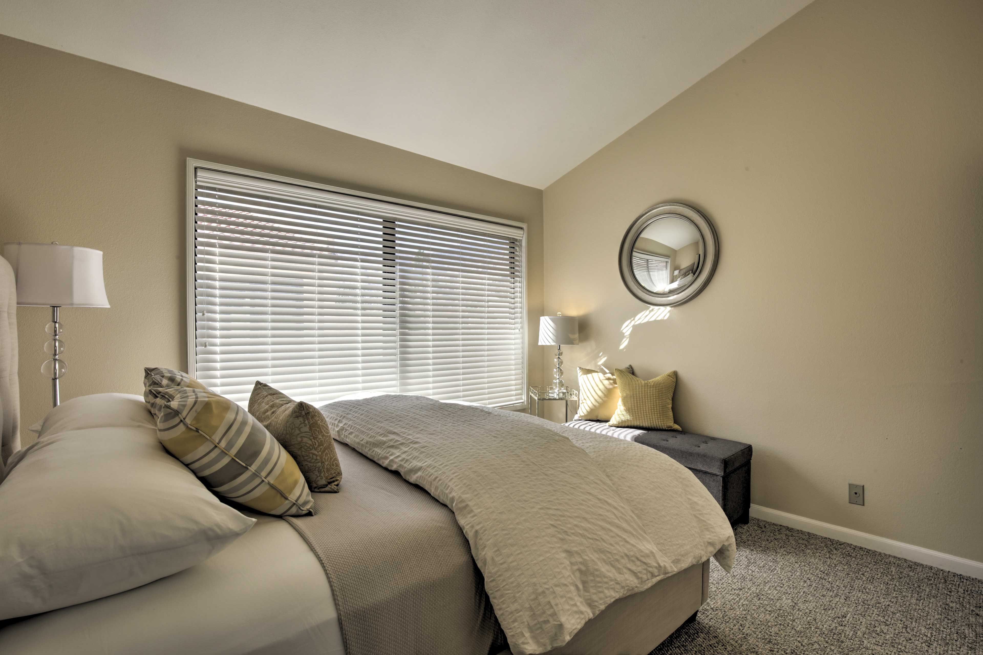This bedroom boasts a queen bed and large window.