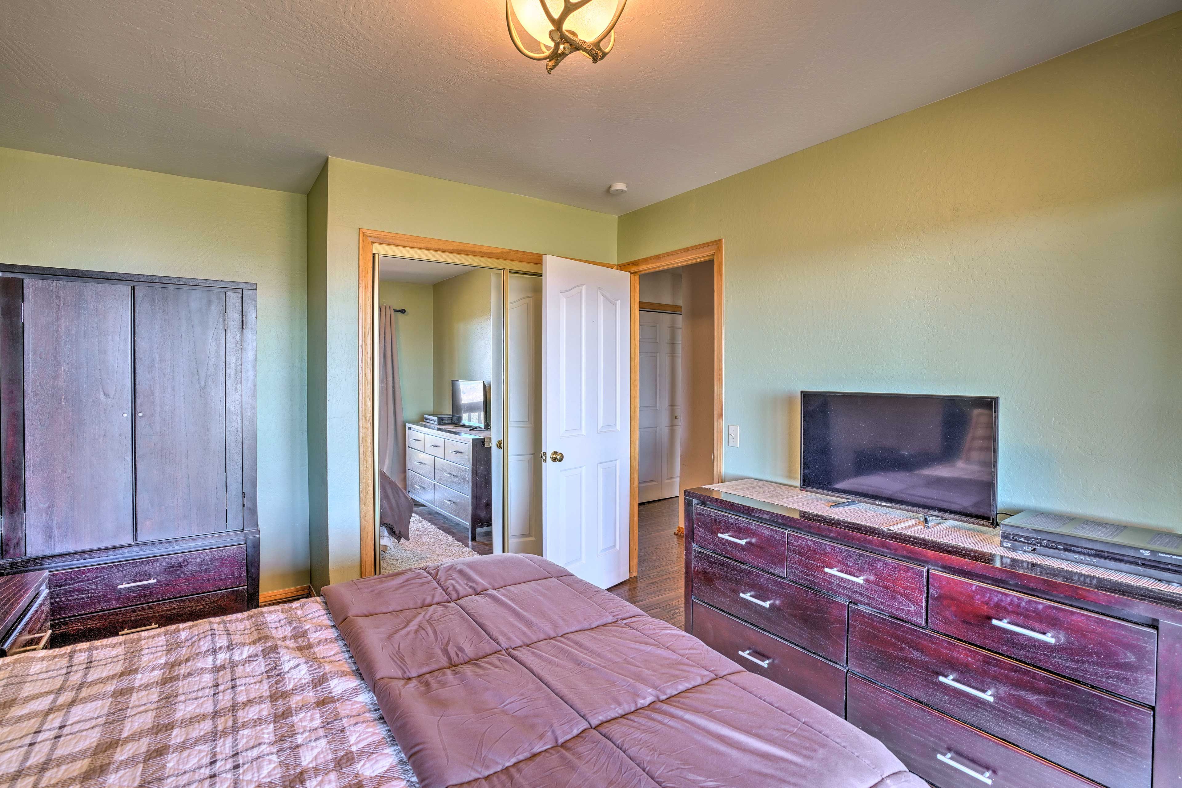 Stow belongings in the large wooden dresser with a flat-screen cable TV on top.