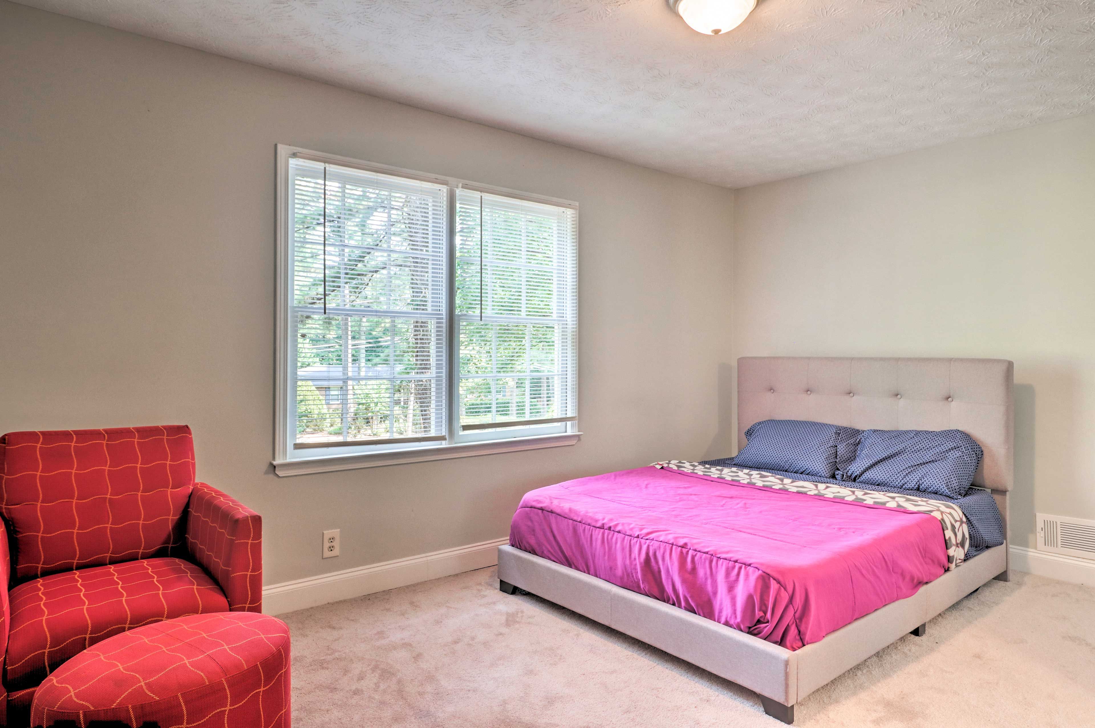 This bedroom features a queen bed and a comfy reading chair.
