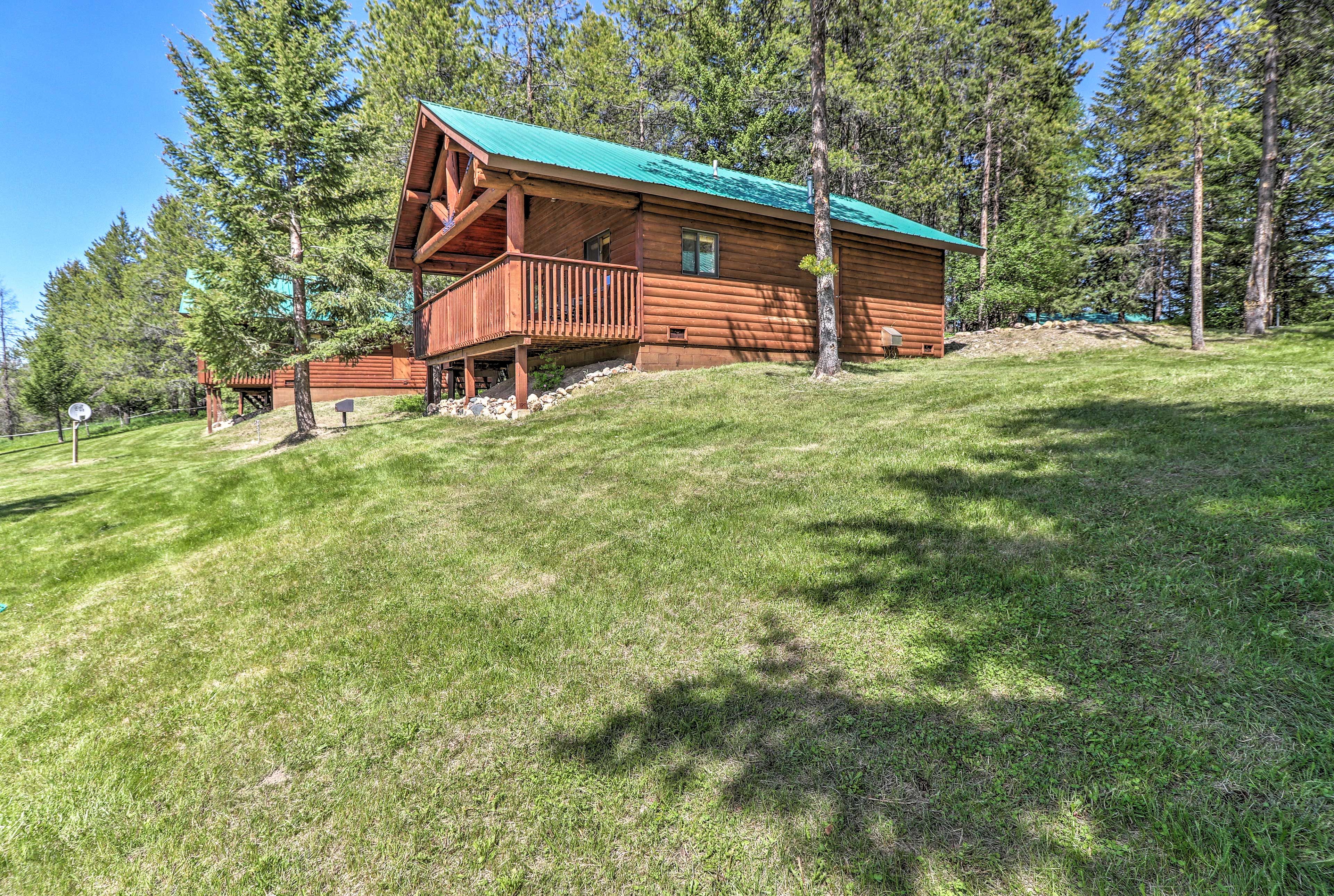 The cabin is nestled into the hills and surrounded by pine trees.