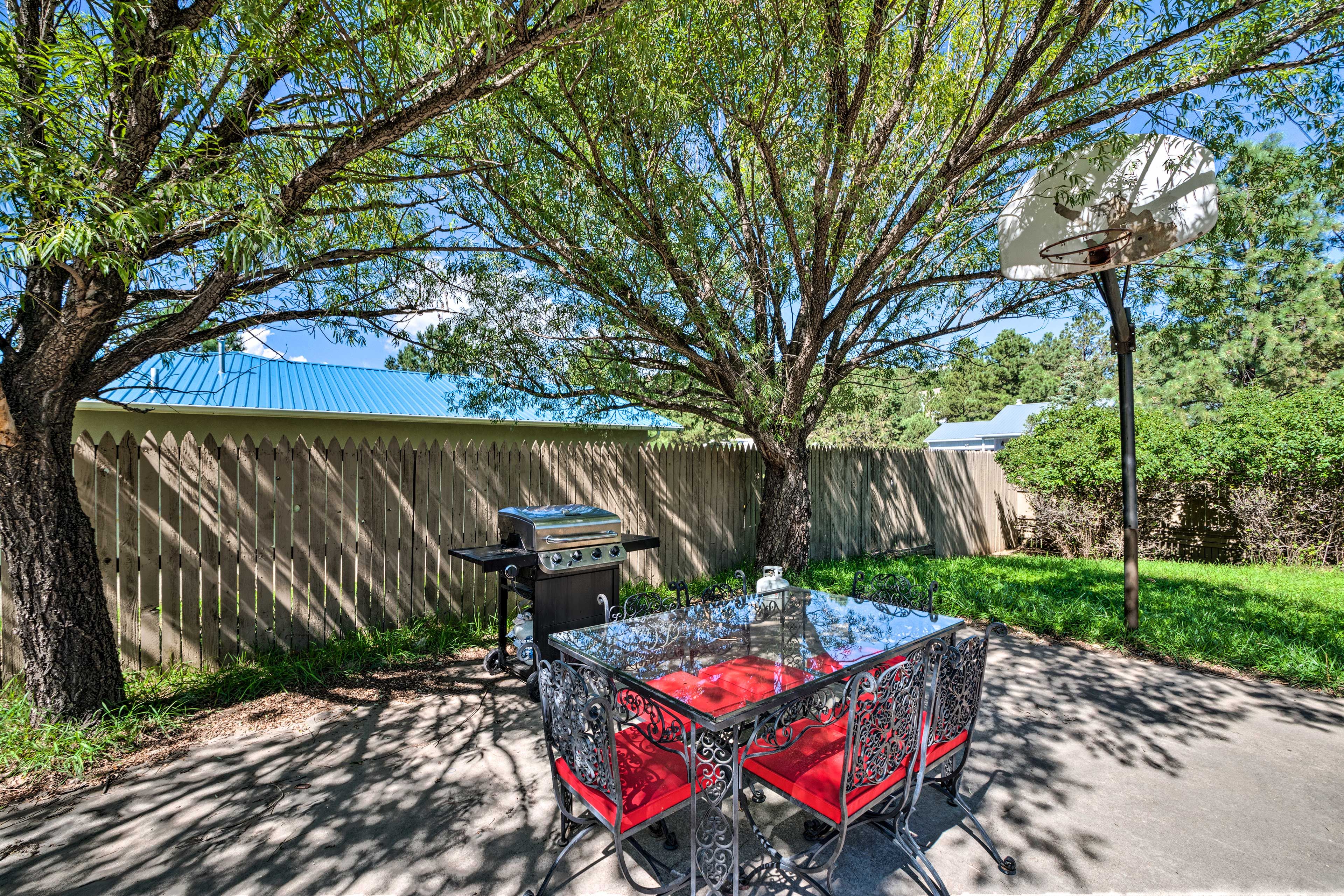 The yard includes an outdoor dining table and gas grill.
