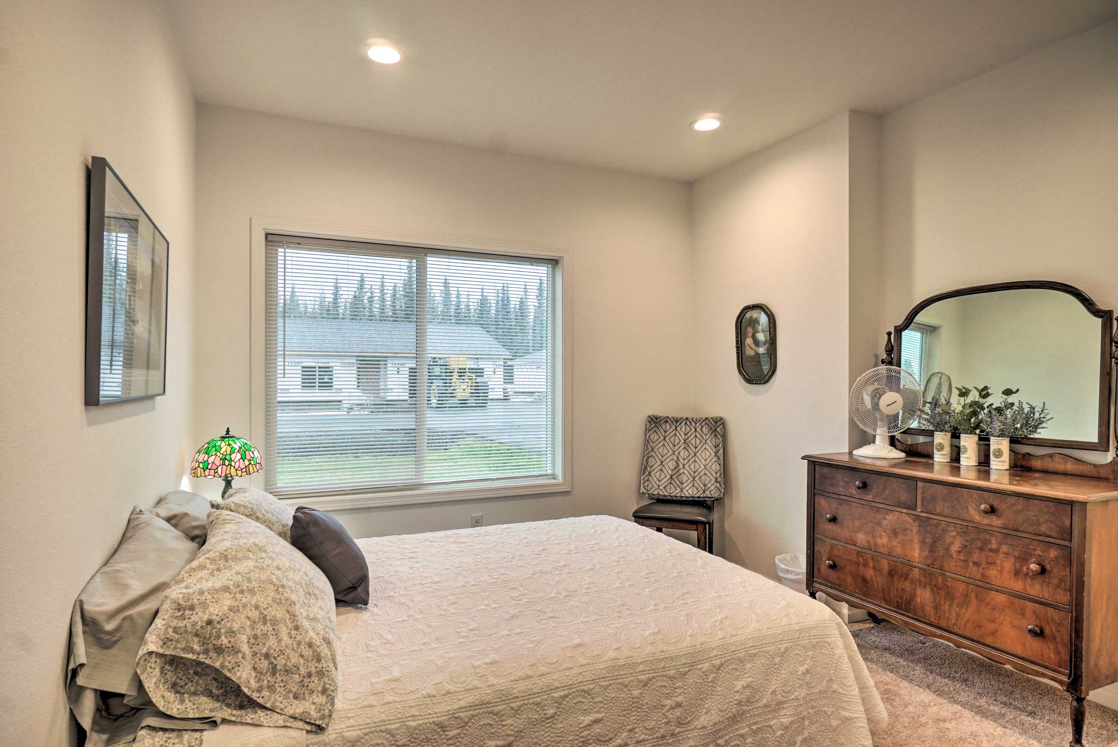 This bedroom boasts a queen bed and an antique dresser.
