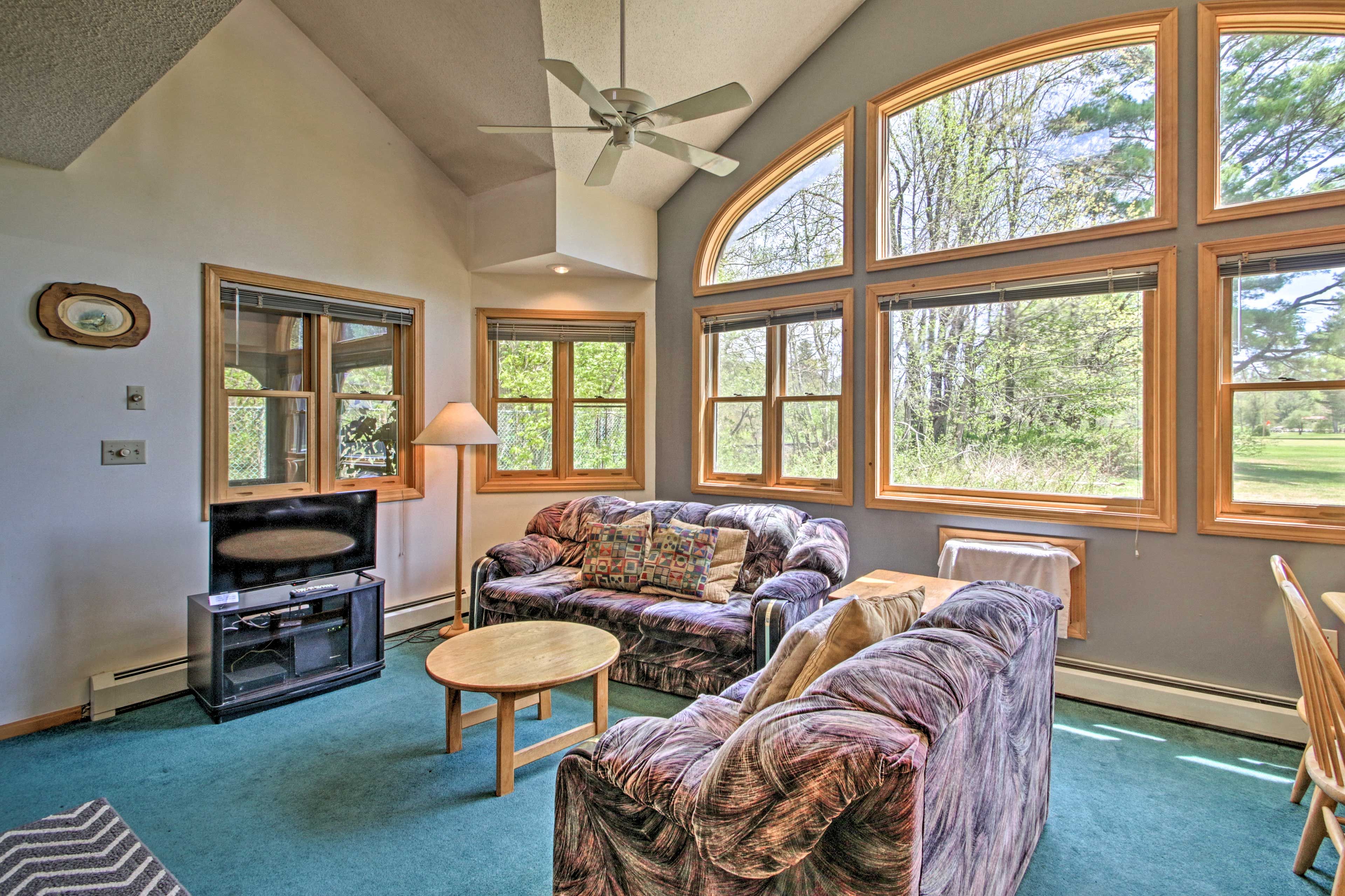 The spacious living room has vaulted ceilings and a view of the greenery outside