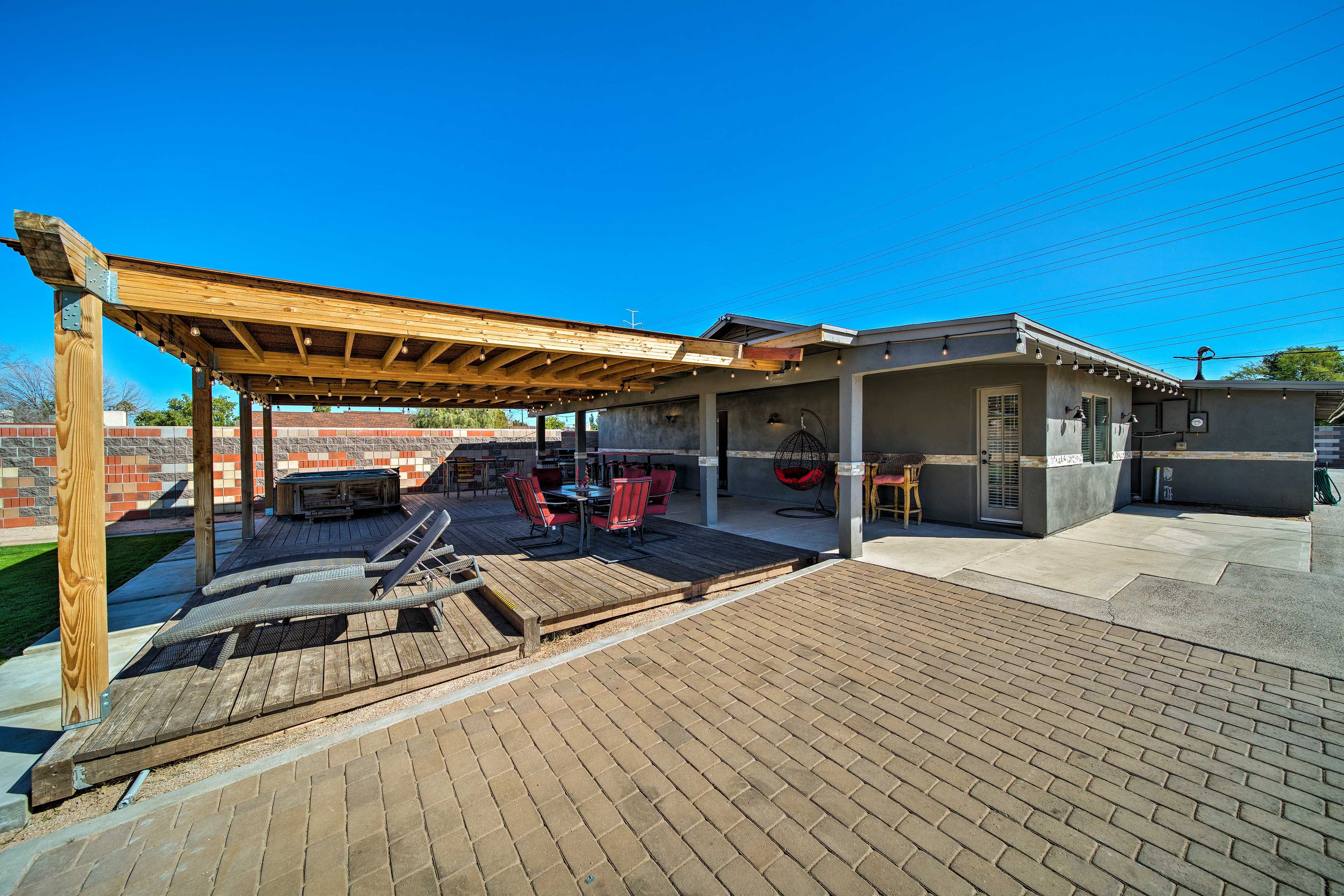 This backyard is complete with a shaded patio, furniture, gas grill and hot tub!